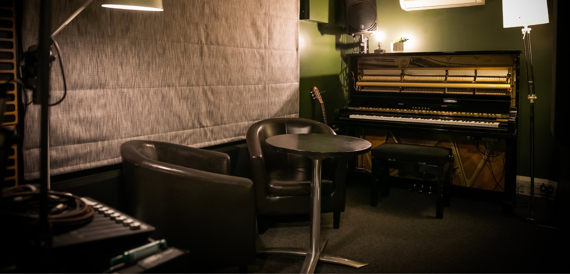 room 3, two chairs at a table in mellow light with piano in background, podcast recorder in foreground